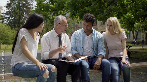 Group of multiracial students discussing science project with teacher outdoors