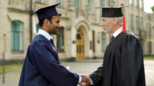 Eminent professor giving diploma to male student shaking hand, successful future photo