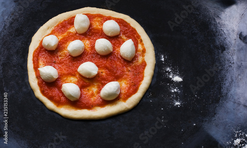 Preparation of homemade pizza with  balls of mozzarella cheese. Ketchup on dough. Cooking process step by step.  Top view on dark metallic background. Top view. Copyspace. Flat lay.