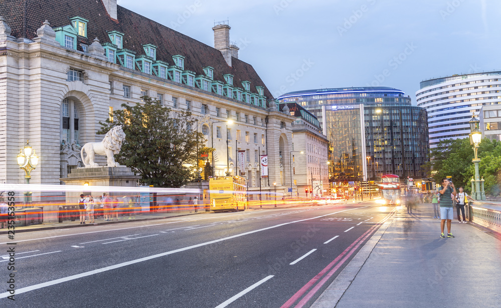 Obraz premium LONDON - MAY 2015: Tourists walk along Westminster Bridge at night. London is visited by 30 million tourists every year