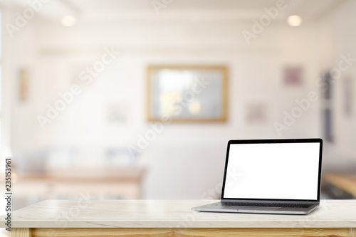Mockup blank screen laptop on marble desk table over living room. © bongkarn