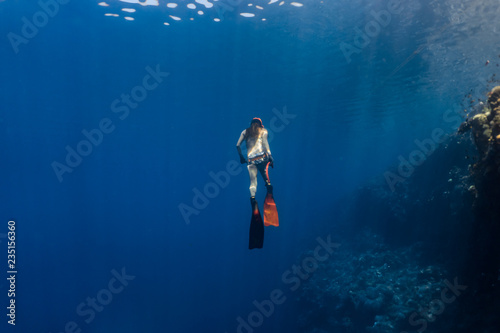 Sexy free diver wearing bikini ascends to the surface from a deep breath hold dive