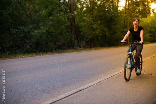 young beautiful girl in sportswear rides a blue bike on the sidewalk