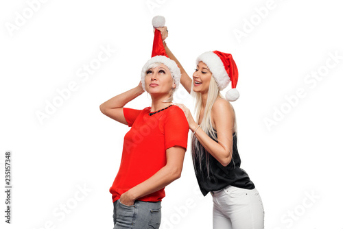 Portrait of a happy and fun mom and daughter posing isolated over white background dressed in Santa hats, black and red clothes. Family relationships, warm hugs