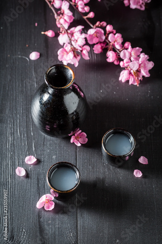 Strong sake with blooming flowers on black table