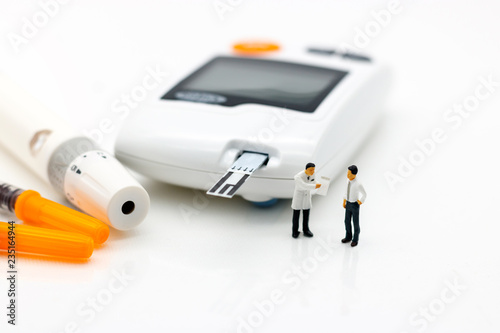 Miniature people: Doctors standing with glucose meter of diabetes  and injection needle , business and health care concept.