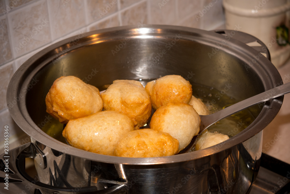 Dipper taking off Dough from a Pot after Friying during the Preparation of an Italian Christmas Traditional Dish called Pettole Dipper taking off Dough from a Pot after Friying during the Preparation of an Italian Christmas Traditional Dish called Pettole