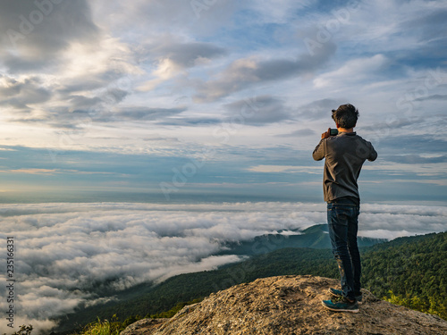 People Take a Picture on the cliff with beautiful sunrise sky on Khao Luang mountain in Ramkhamhaeng National Park,Sukhothai province Thailand