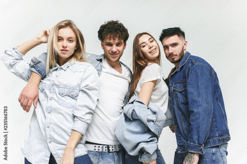 Group of smiling friends in fashionable jeans. The young men and woman posing at studio. The fashion, people, happy, lifestyle, clothes concept Group of smiling friends in fashionable jeans. The young men and woman posing at studio. The fashion, people, happy, lifestyle, clothes concept