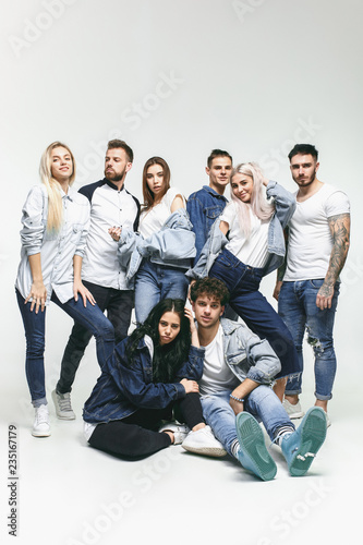 Group of smiling friends in fashionable jeans. The young men and woman posing at studio. The fashion, people, happy, lifestyle, clothes concept