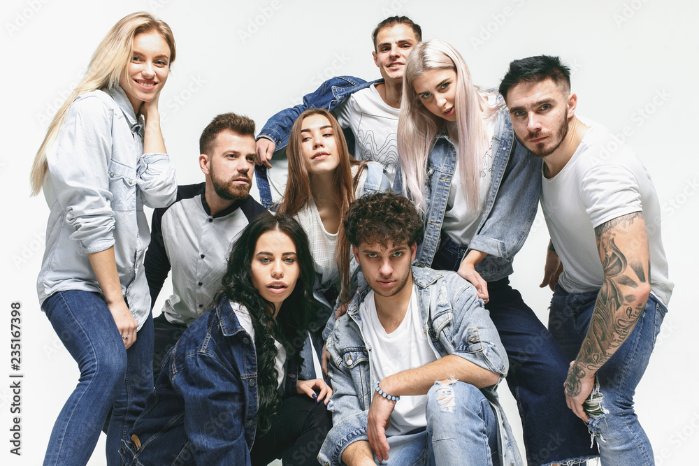 Group of smiling friends in fashionable jeans. The young men and woman posing at studio. The fashion, people, happy, lifestyle, clothes concept Group of smiling friends in fashionable jeans. The young men and woman posing at studio. The fashion, people, happy, lifestyle, clothes concept