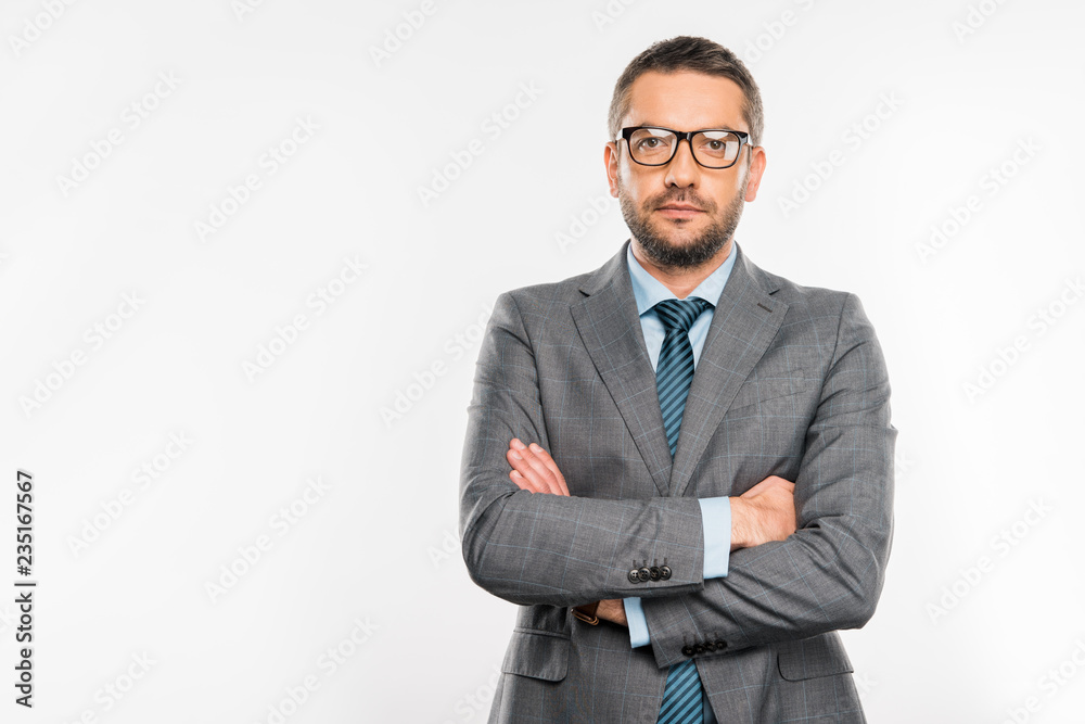 confident businessman in suit and eyeglasses standing with crossed arms and looking at camera isolated on white confident businessman in suit and eyeglasses standing with crossed arms and looking at camera isolated on white