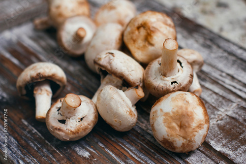 Champignon mushrooms. Small white brown mushrooms on wooden table. 