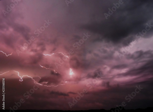 magenta and black cloudy sky at night with long strong boomerang high voltage lightning 