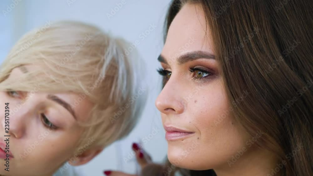 closeup view of model girl getting professional makeup by makeup artist at beauty salon. people, cosmetics, care, lifestyle, style concept closeup view of model girl getting professional makeup by makeup artist at beauty salon. people, cosmetics, care, lifestyle, style concept