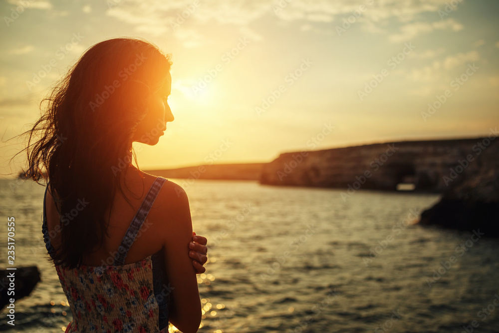 beautiful woman looking into the distance at sunset against the sky