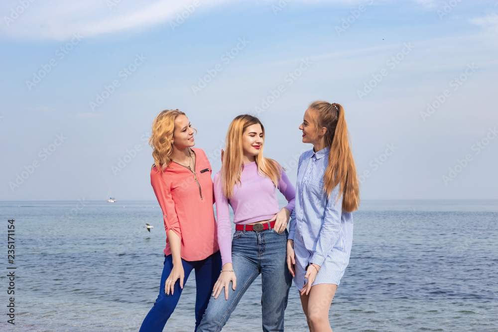 Portrait of three young female friends walking near sea