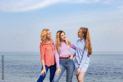 Portrait of three young female friends walking near sea © Ivan