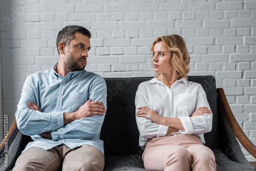 couple sitting on couch after quarrel and looking at each other