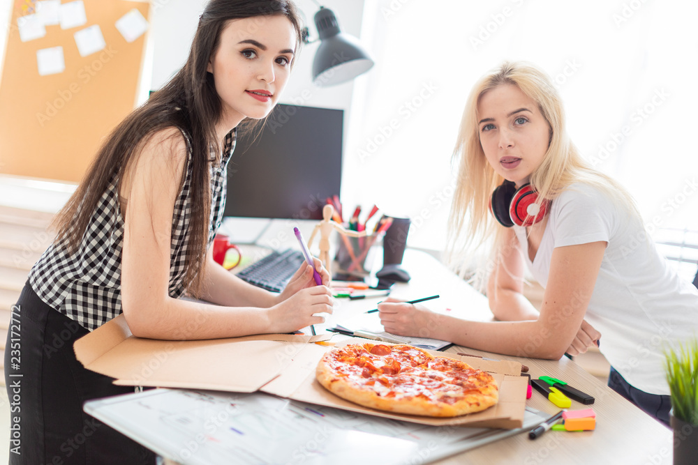 Two girls eating pizza in the office. Two girls eating pizza in the office.