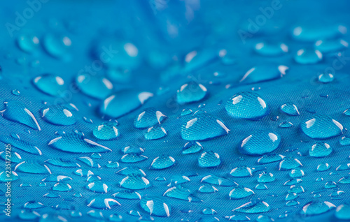 Water drops on waterproof nylon fabric. Macro detail view of texture of blue woven synthetic waterproof clothing. Waterproof fabric with water drops. Rain Drops on Water Resistant Textile. photo