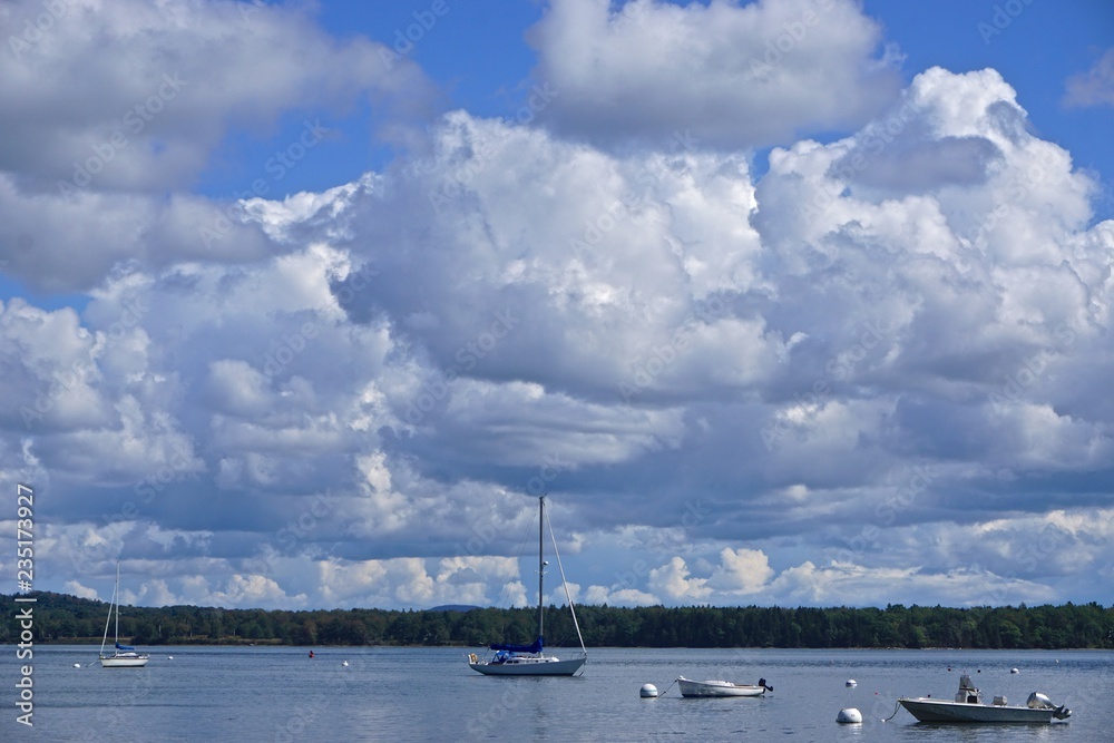 Castine, Maine, USA: Small boats in the waters of Penobscot Bay, under a blue sky with dramatic white clouds overhead.