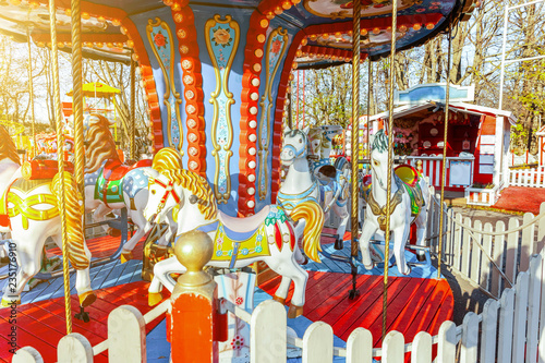 Children outdoor colourful vintage Merry-Go-Round flying horse carousel in amusement holliday park in city. Attraction detail horses and animals with lots gold paintwork on traditional retro carnival photo
