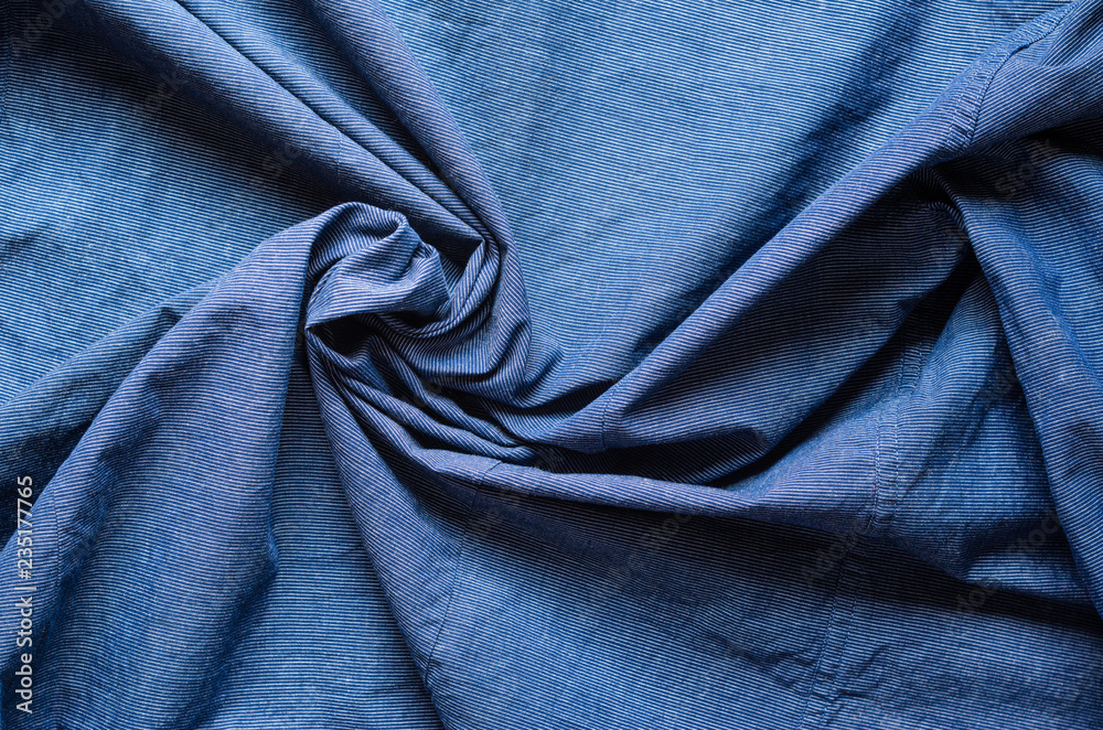 Twisted in the center cloth swatch. Wrinkled texture of blue fabric for shirts. Blank textile background Twisted in the center cloth swatch. Wrinkled texture of blue fabric for shirts. Blank textile background