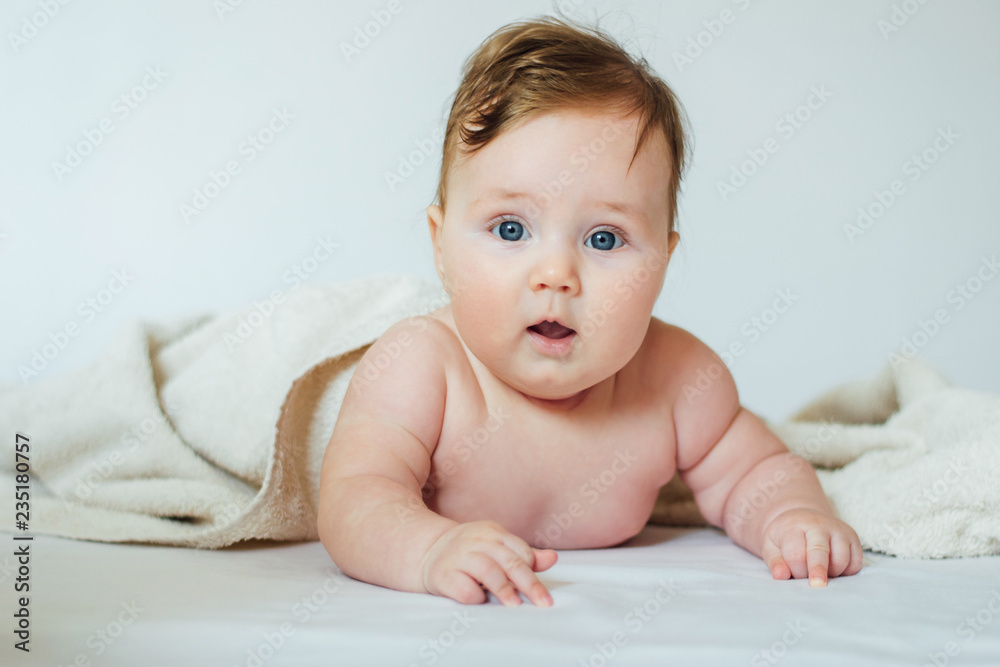 Cute baby covered with a bath towel lying on tummy