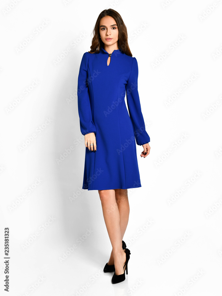 Young beautiful woman posing in new dark  blue fashion winter dress on a white