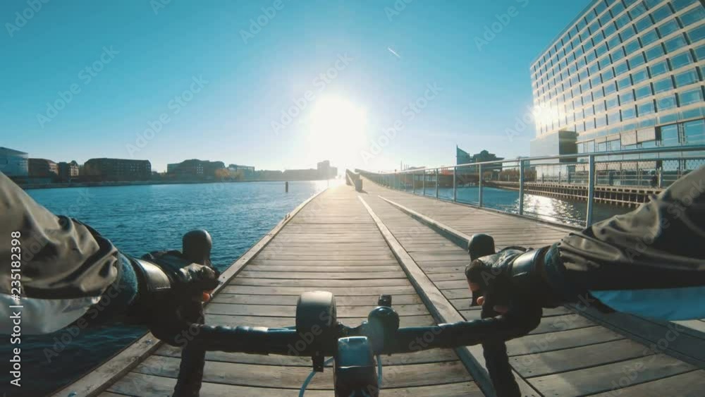 Point of view of athlete riding bicycle next to harbour as sun sets
