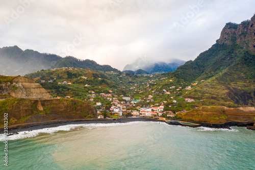 Aerial view of the Porto da Cruz town in the north shore of Madeira island with mountain range in the heavy clouds. Madeira, Portugal. photo