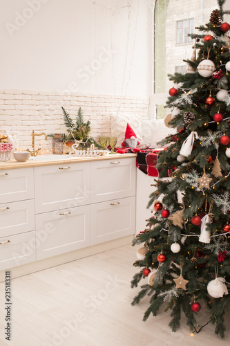 Interior light kitchen and red christmas decor. Preparing holiday dinner at home on the kitchen concept. Decorated new Year fir. Selective focus