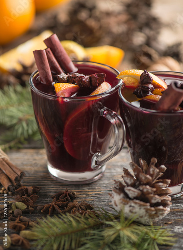 Hot alcohol winter fragrant beverage mulled wine in the glass cups on a wooden rustic background, place for text.