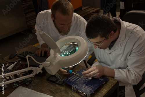 Robotics engineers assembling circuit board at desk