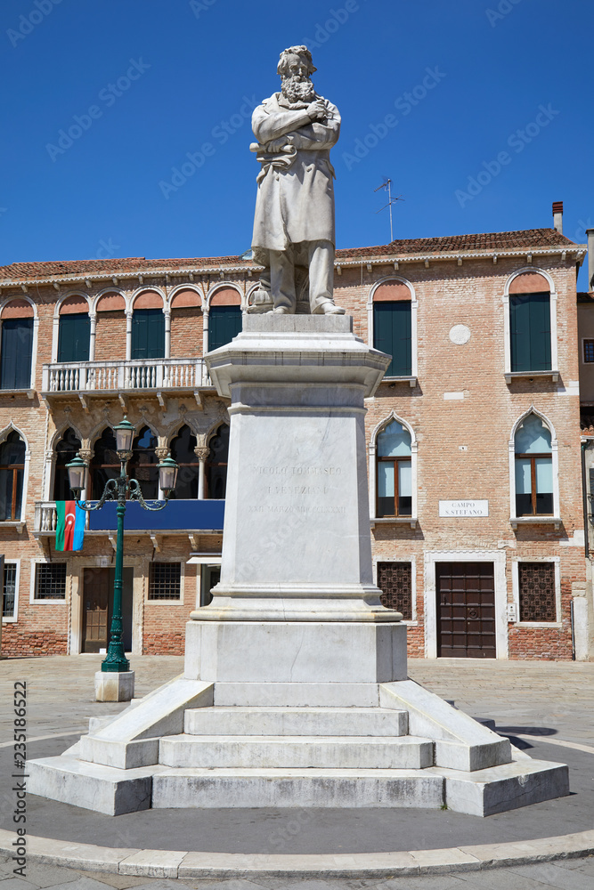 Niccolo Tommaseo statue with pedestal in Venice by Francesco Barzaghi (1839-1892) in a sunny summer day in Italy