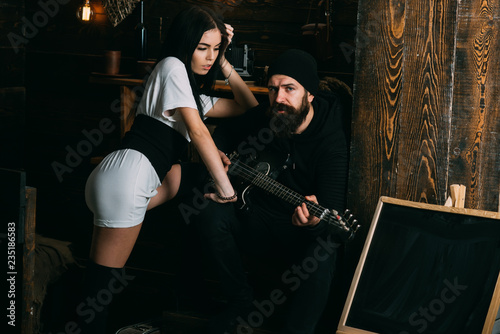 Playing from his heart. Romantic couple of brutal man and sexi woman. Bearded man play guitar to sexy woman. Couple in love enjoy music. Rock style couple of lovers. Man guitarist play for girlfriend