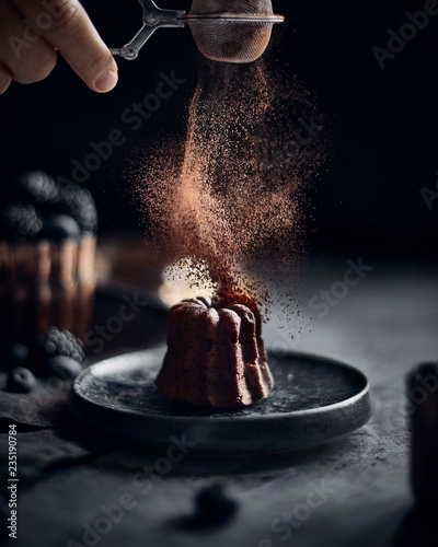 Man sprinkling cocoa on mini chocolate lava bundt cake photo