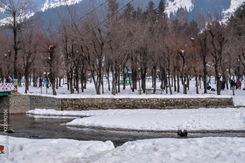 Stunning snow landscape with snow covered mountains and beautiful river in Betaab Valley, Pahalgam. Snow covered forest & forest lodges during Christmas/New Year holidays in Kashmir, India. photo