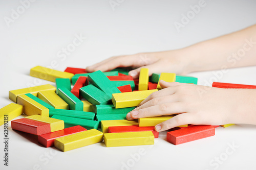 Details puzzle tower. Children's hands are located on a pile of puzzle blocks. White background. Close-up.