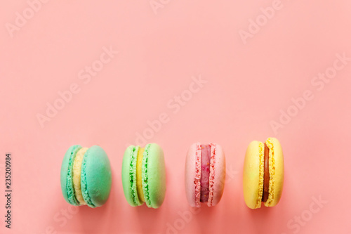 Sweet almond colorful pink blue yellow green macaron or macaroon dessert cake isolated on trendy pink pastel background. French sweet cookie. Minimal food bakery concept. Flat lay top view copy space