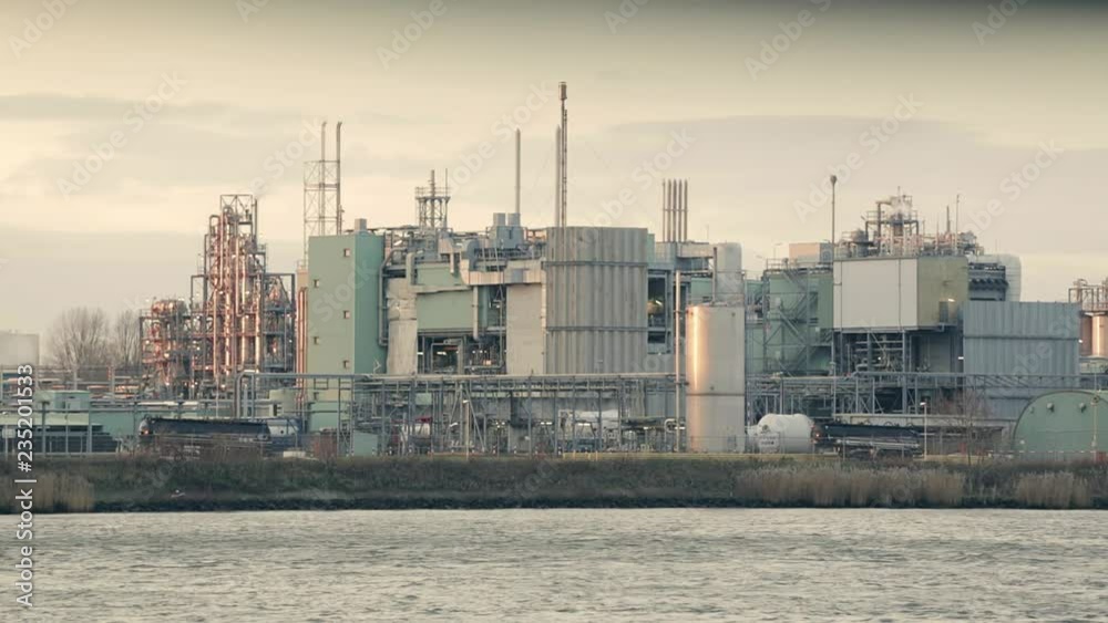 Early morning (or sunset) view of a chemical plant or a factory by a river. Early morning (or sunset) view of a chemical plant or a factory by a river.