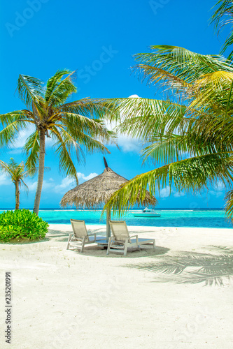 Beautiful sandy beach with sunbeds and umbrellas in Indian ocean, Maldives island
