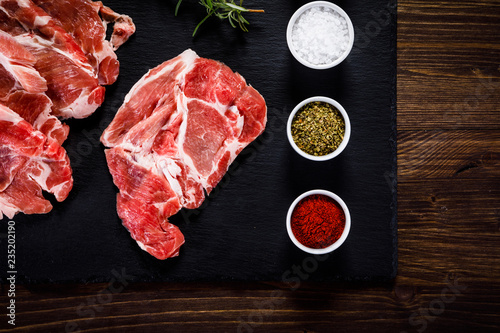 Raw beefsteaks on black stone on wooden background