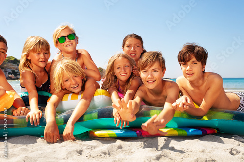 Happy friends sunbathing on sandy beach in summer