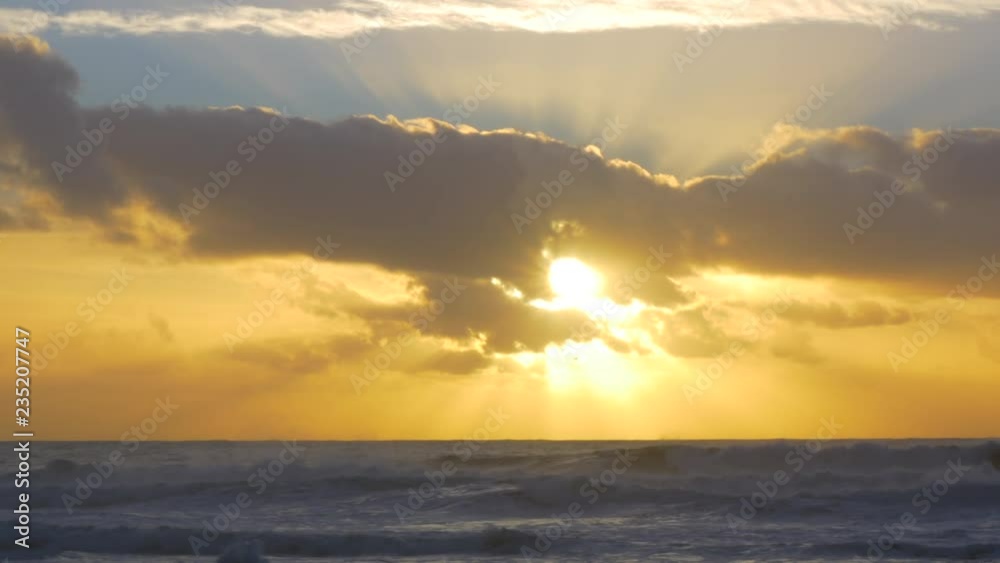 Beautiful setting sun between clouds over ocean at sunset in Portugal Beautiful setting sun between clouds over ocean at sunset in Portugal
