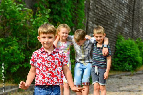Four happy and joyful children, a boy in red clothes is in the foreground, and his friends are behind.