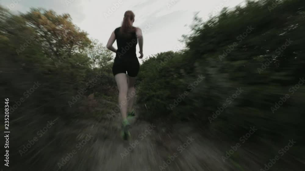 A female cross country runner training on a narrow beach trail by sunset in the summer. A female cross country runner training on a narrow beach trail by sunset in the summer.