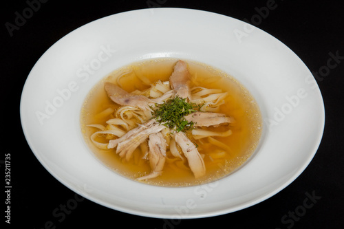 Chicken soup in a white plate on a black background
