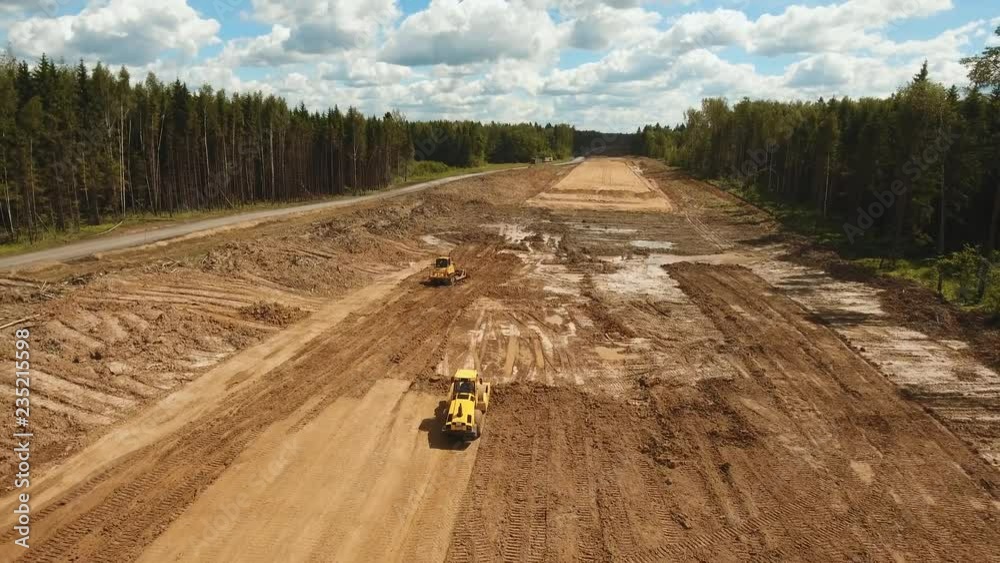 Construction of a new road in the forest area. Aerial view construction road place. Construction machinery for the construction of a road in the forest. 4K, flying video, aerial footage